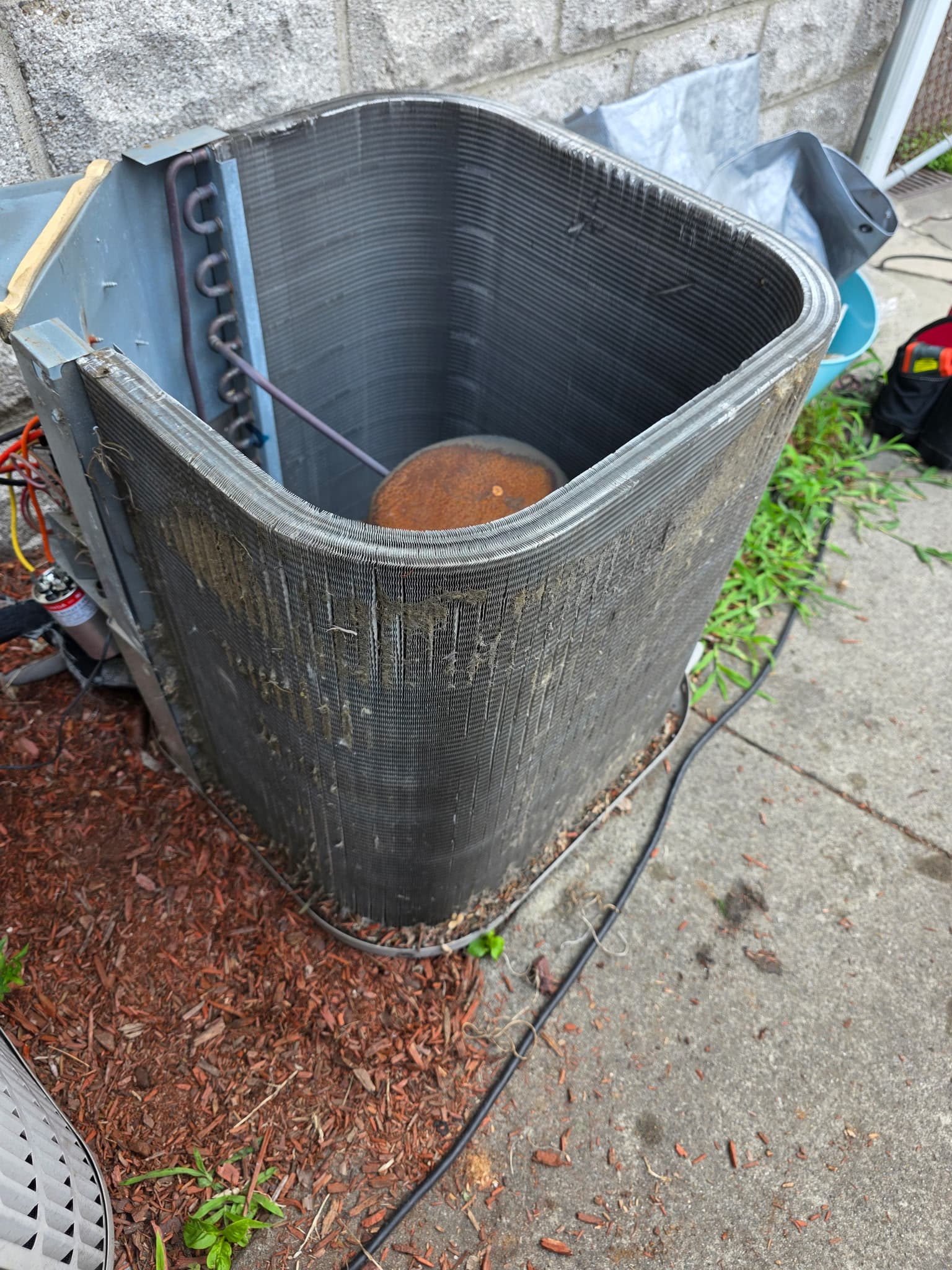 Disassembled outdoor air conditioner unit with dirty condenser coils and a rusted internal motor.