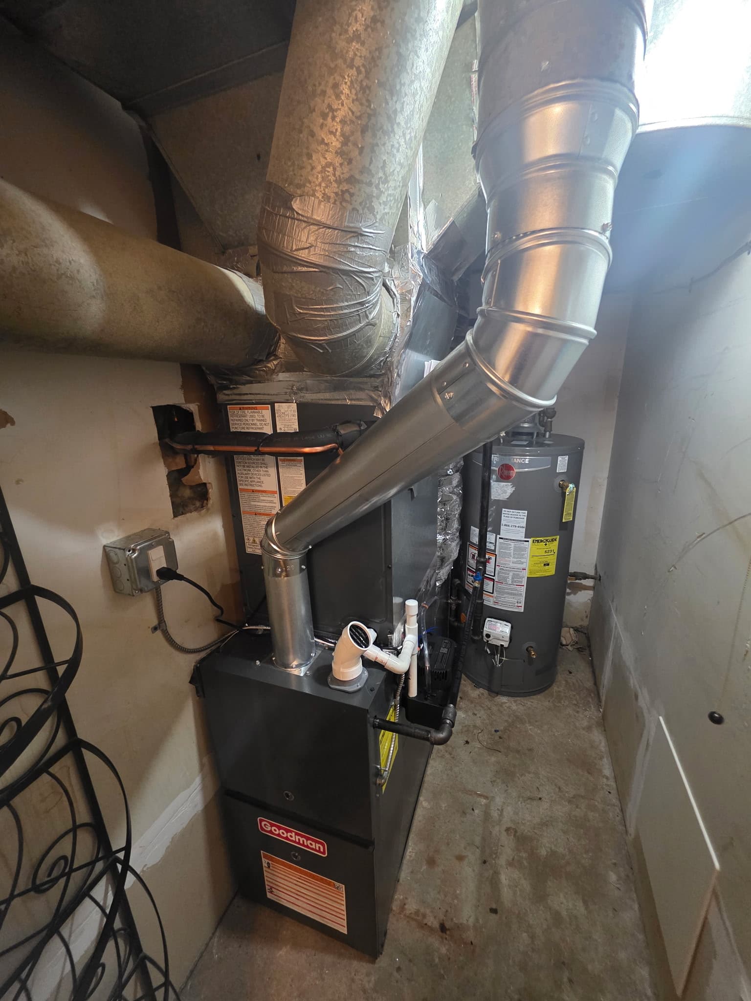 Goodman furnace and Rheem water heater with metal ductwork in a basement utility room.